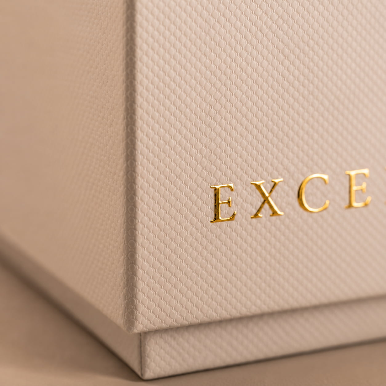 Detalle de la caja rígida de una vela Excentropía con acabado texturizado y logotipo dorado.