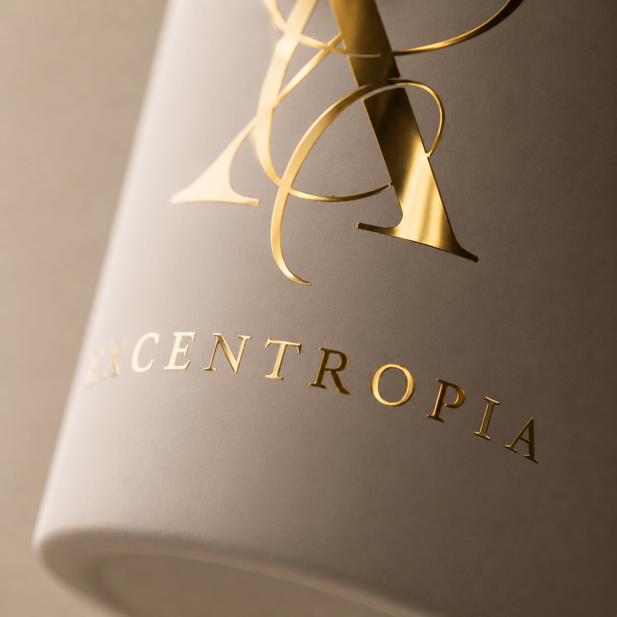 Detalle del logotipo dorado sobre el recipiente de una vela artesanal Excentropía.